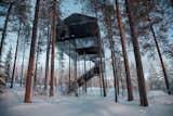 The 7th Room is a remarkable accommodation at Sweden’s Tree Hotel that blends into its natural surroundings with a stark black facade. Snøhetta designed the structure, which features an expansive, black-and-white mural of the tree canopy stretched across its base. You can sleep in the beautiful cabin—or if you are brave, under the stars in a giant lofted hammock slung between the two bedrooms.