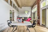 Towards the front of the house, where the original garage doors have been replaced by French doors and transom windows, is a multifunctional space with brick walls that currently functions as an office.