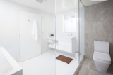 "We kept to a very simple and streamlined palette and carefully selected light fixtures that echoed the lines and movement within the space," says Misra. The monochromatic bathroom features a custom white lacquer vanity and Porcelanosa tiles. &nbsp;