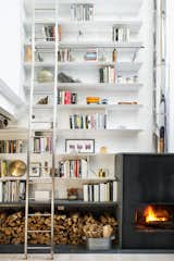 The double-height living room provided the perfect opportunity to combine the homeowners' love of art, literature, and travel, allowing them to fill the 24-foot shelves with books and collected artifacts. A wood-burning sustainable fireplace by Wittus adds a broad stroke of warmth. &nbsp;