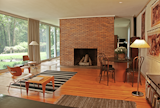 Reminiscent of the Glass House, a monumental brick fireplace stands in the center of the living room.
