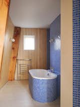 Bath Room, Light Hardwood Floor, Soaking Tub, Wall Lighting, Freestanding Tub, and Ceramic Tile Wall  Photo 6 of 14 in Resembling the Inverted Hull of a Ship, an English Guest House Pays Homage to the Harbor