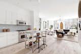 Kitchen, Microwave, Range, Wall Oven, Recessed Lighting, Light Hardwood Floor, Pendant Lighting, Quartzite Counter, White Cabinet, and Glass Tile Backsplashe  Photo 2 of 10 in This American Life’s Ira Glass Lists His Light-Filled Chelsea Apartment For $1.75M