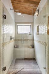 The ensuite bathroom features a tiled shower with a built-in bench and a wood-slat floor.
