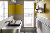 Playful touches abound, evident in the bathroom, which features yellow paint, stainless steel, and white tiles. A deep bath—a plunge pool of sorts—and shower are on the other side.