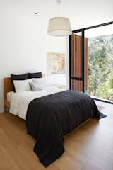 A bedroom is bathed in light while enjoying the seclusion of the tree-filled setting. Wide-plank oak floors contrast with the large format tiles covering the public spaces.&nbsp;