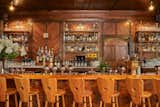 Field Theory ordered brass brackets from Iron Abode, and a local carpenter created custom shelves to match the wood paneling. Carrara marble counters run underneath them. The oak-and-iron midcentury bar stools were from 1st Dibs.