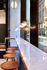 BIT UNION AKERSGATA (OSLO): Fashioned of marble with brass trim, the cool and clean street-facing bar finds a warm counterbalance in its contoured oak stools. 

Photo: Paul Paiewonsky
  Photo 4 of 10 in Bespoke Oasis in Bustling Oslo by Montaag Design