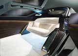 Interior details include an expansive OLED touch-screen, Macassar wood paneling, deep-pile ivory wool carpet, and a silky wool sofa. A luggage compartment is hidden near the front wheels.