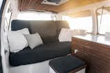 Cargo Van Mobile Studio Living Area with cushioned bench and decorative pillows and throw
