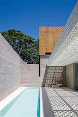 Located in São Paulo, Brazil, this outdoor space designed by Figueroa Arq employs both poured-in-place concrete and perforated concrete blocks to produce a strong contrast between the white-and-orange lattice of the blocks and the solid walls of the gray concrete.&nbsp; Photo by Leonardo Finotti