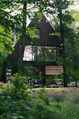 Jean Verville architecte designed FAHOUSE, a residence burrowed in the middle of a hemlock forest in Eastern Townships, Canada. The design takes inspiration from the archetypal figure of a house and doubles it with two triangular prism forms that are connected – almost like two trees growing towards the sky.