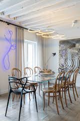 The dining room features a Glas Italia table that’s paired with vintage Thonet chairs and two black Kartell chairs. The neon art is by Gun Gordillo and the piece on the right is by Alexandre Arrechea.