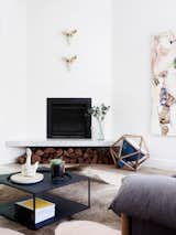 At a modern, renovated home in Melbourne designed by NORTHBOURNE Architecture + Design, a new fireplace was installed above a marble hearth that doubles as a bench with storage for firewood underneath.
