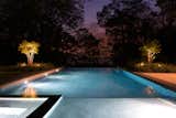 The pool, lighting, and landscape frame dramatic views of sunsets over the Long Island Sound.