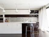 The monochrome kitchen opens out onto a terrace. Joinery by Space Joinery, Lighting by Tangent Light , splashback design by Jane McNeill, Tiles by Bisanna Tiles
© Justin Alexander