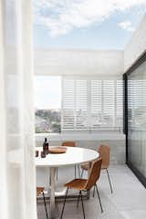 Thanks to the shutters that form private screens when viewed from the street, the residents can enjoy easy-breezy outdoor dining without having to worry about privacy. 

  Photo 16 of 16 in This Resurrected Beach Home Near Sydney Stands on a Concrete Leg from Tama’s Tee House - A Coastal Concrete Unipod