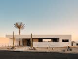 Front elevation of desert modern new home in Phoenix Arizona featuring breeze block, wood slats, date palm tree aperture, and pocketing sliding glass doors