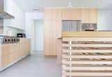 The oversized kitchen island utilizes a structure of aluminum spacers at maple slats to support the plywood and stainless steel top.