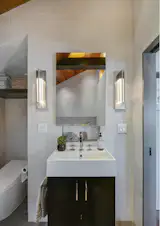 Modern ensuite bathroom vanity flanked by Hubbardton Forge Axis sconces.