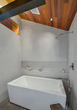 Deep porcelain soaking tub and wood covered vaulted ceilings, add luxury touches to the master bath.
Dean had to balance the practical elements and lack of space with things he really wanted—always asking himself, “What do I absolutely need?” In the end, he didn’t have to sacrifice anything at all. “After having lived all over Seattle, I learned that I don’t need a big space. This houseboat was within walking distance to great restaurants, my shop, and it was low-maintenance. Absolutely perfect.”