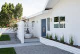 Modern light fixtures in a midcentury style meet more bohemian elements like an ocean blue door and spiritual meditation statue.