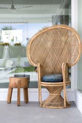 A bohemian rattan chair with vintage pillow and wooden stool accessorize the outdoor area by the pool.
