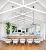 “When in doubt, go with white” was a guiding design principle on this project by interior designer Eric Ford.Exposed wooden white beams create unique patterns in the open concept living and dining room, floating high above the table for twelve.