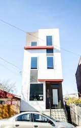 The row house façade takes a playful tone, with a mix of exterior cladding materials and horizontal red projections dividing up the three stories and making the narrow parcel stand out.
