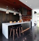 The kitchen anchors the primary living space of the house and utilizes cherry wood harvested from the site as wall and ceiling paneling
