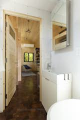 The acrylic lined bathroom holds a low-profile sink and a waterless toilet. Because the space is small, the mirror slides to the side to reveal the medicine cabinet.  Photo 5 of 23 in SaltBox Tiny House by Extraordinary Structures