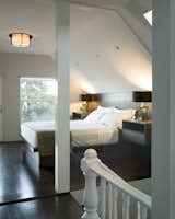 The glass half-wall opens up this lofted bedroom, lit by the Soleil Ceiling fixture by Boyd Lighting.