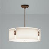 Four curved sections of white glass supported by four wood-grained metal clips comprise a cylindrical diffuser. The canopy of this pendant is also wood-grained for an elegant play on modern-meets-rustic. Stunning in foyers, living rooms and dining rooms. Clean lines that work well in residential, commercial and hospitality applications. Available in four bronze metal finish options. #pendant #lighting #drumshade #drumpendant