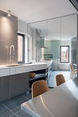 The counter and mirrored pantry meet obliquely enlarging and distorting the space of the kitchen