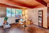 Original details in the living room include wall paneling, stained tongue-and-groove ceilings, stained beams, and doors on either side of the fixed-pane windows that open to louvres for cross ventilation, when desired.