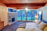 The spacious master bedroom was added after the home was built, and was designed by the home’s original builder and designer, Edward Hawkins. A modern fireplace with glass above the hearth provides and unique architectural element, while a window wall looks out into the spacious back yard. The same architectural language of wood paneling, stained tongue-and-groove ceilings, and exposed pumice block extends into the addition (although previous owners added drywall over the original pumice block in this room).