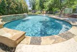 This custom freeform pool was strategically placed in the backyard to allow the homeowners to soak up the sun or relax in the shade, depending on their preference. The water features provide a soothing ambience for this home near downtown Austin, TX.  Photo 10 of 11 in A Pool In Austin Built For Relaxing by TimberTown