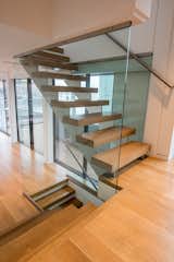 Custom stainless steel stair treads with Oak floating stairs and full height glass panels.