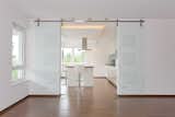 A modern barn door  used in a white living space. The stainless steel hardware gives it a sleek modern finish. Get inspired -> www.bartelsdoors.com