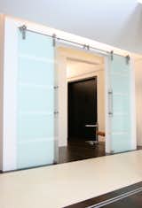 A modern barn door using glass creating a divide between two living spaces.