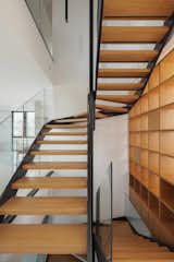 The sweeping staircase in CK House by Christiana Karagiorgi Architects runs alongside the home's wooden library.