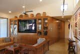 The built-in cabinetry showcases some of the owner's extensive Native American collection and wraps around the corner as a paneled wall with hidden doors that lead to a half bath and a small office. Stained concrete floors. 