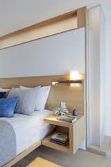 The transom window above and the adjacent full height glazing allow light to filter into the bathroom beyond. Integrated bedside lighting can pivot to either side for better night time reading.