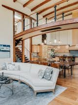 Living Room, Ceiling Lighting, Sofa, Coffee Tables, Medium Hardwood Floor, and Pendant Lighting "At the interior, wood columns reach to arched beams and rafters, forming a canopy high above. Corner windows throughout make an immediate connection to nature, and the verticality of the trees outside. On a very visceral level, walking across the central bridge takes us back to our primal canopy," says Armin.

And indeed it does - upon entering the home, one is immediately struck by the great room's 20+ foot high arched beamed ceilings and a curved bridge that runs through the center of the home.  A curved sofa by Ted Boerner sits gracefully in the living room and can be separated and reconfigured for flexible seating around the fireplace. A Ted Boerner coffee table compliments this form and adds another layer of materials with its bronze metal accents.  Against the far wall we see a painting by renowned artist Raimonds Staprans.  All of the furnishings and artwork are available to purchase - a true delight for those looking for a turnkey sanctuary as many pieces were custom designed specifically for this home.

Curved forms are a theme repeated throughout the residence and Armin explains, "Just like repeating melodies and patterns in a musical composition, repeating architectural shapes and forms bring us deeper understanding and comfort. In the Ridgeview House, shapes as small as the edge of a tile, the top of a base-board, to countertops, doors and backsplashes, all the way up to the overall shapes of the roofs and decks - all relate to one another, creating a cohesive theme. The repetition of these forms and shapes is the handprint of this home’s design. It’s what makes the Ridgeview House unique; but more importantly, it’s what makes it cohesive, comfortable, and sublime."  Photo 2 of 15 in Contemporary Masterpiece by DAVIS GONTHIER