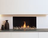 A low cupboard topped with a thick slate hearth, behind a black finished aperture features our fire pebbles. This fire creates beautiful a modern open look.