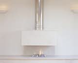 A room-length limestone shelf contains a Soctates burner with fire pebbles to create an open and contemporary look. This gas fire creates a stunning focal point in any room.