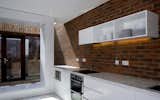 White Cabinet, Brick Backsplashe, Microwave, Marble Counter, Kitchen, and Track Lighting  Photo 4 of 10 in Brick-A-Brack House by Urban-Agency Architects