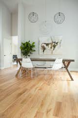 Off white walls, a farmhouse table and a wire pendant reminiscent of a bird’s nest are coupled with an oversized painting.