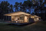 Outdoor, Wood Patio, Porch, Deck, Small Patio, Porch, Deck, Grass, and Back Yard Casa Bosque, which sits in a forest along the Argentine Coast, hugs a sloping, 6-foot dune.  Photo 3 of 8 in A Staggered Concrete Home in Argentina Nestles in the Woods