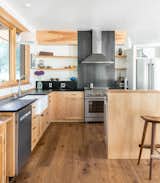 Kitchen — a simple material palette of alder wood cabinets and soapstone countertops are accented by an oiled steel backsplash and fired clay, farmhouse sink.